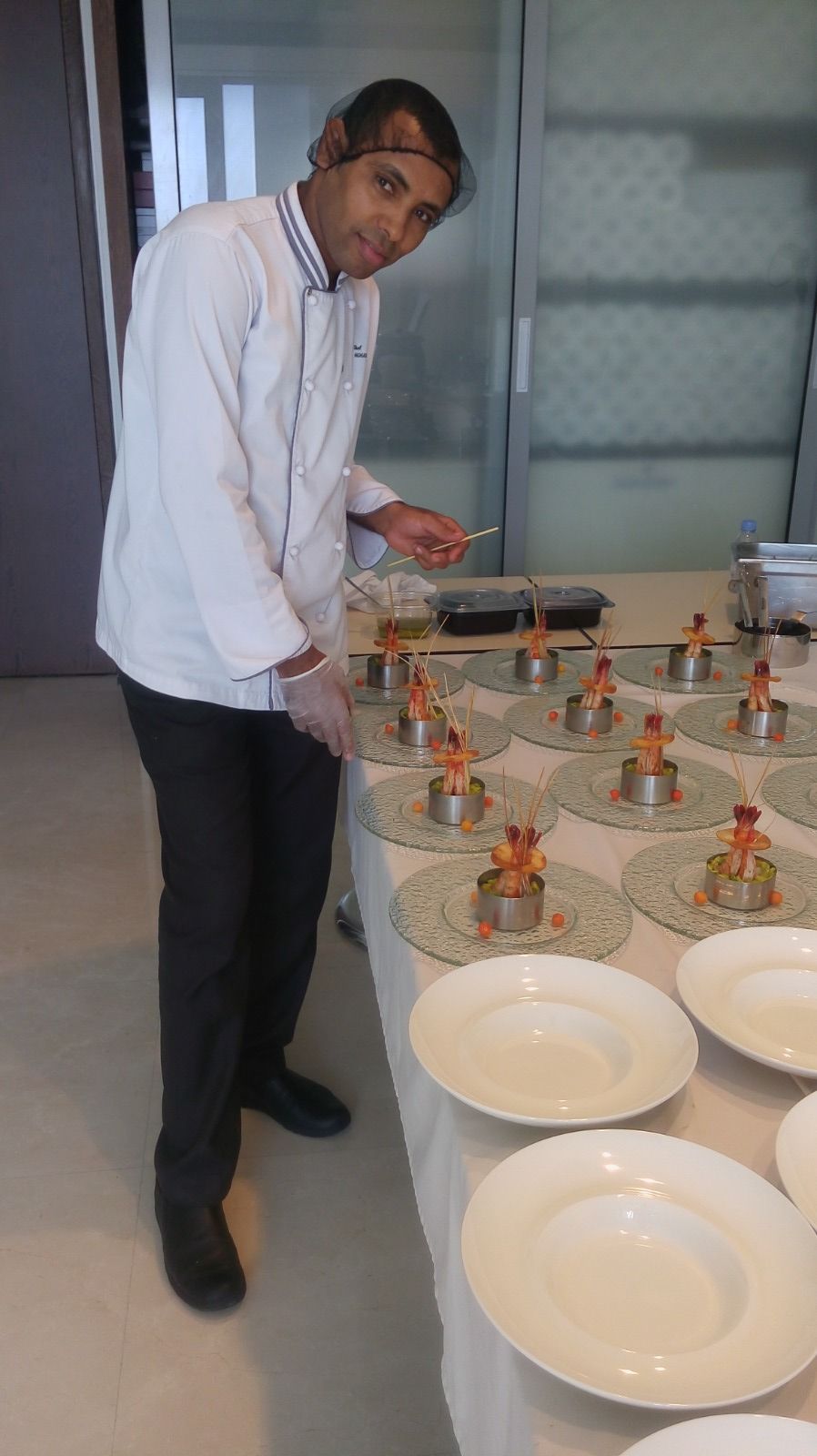 Chef checking a plating line of shrimp amuse-bouche